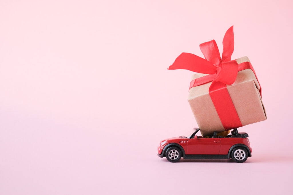 international gift reseller mini cooper car holding gift pink background 
