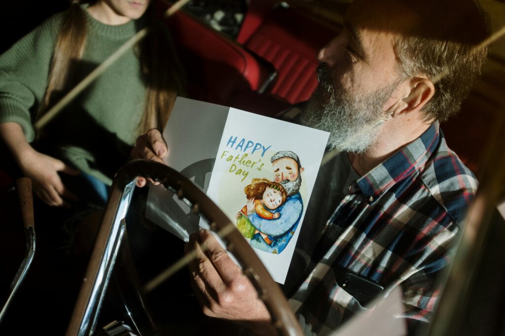 father's day gift guide father holding father's day gift card in the car with daughter